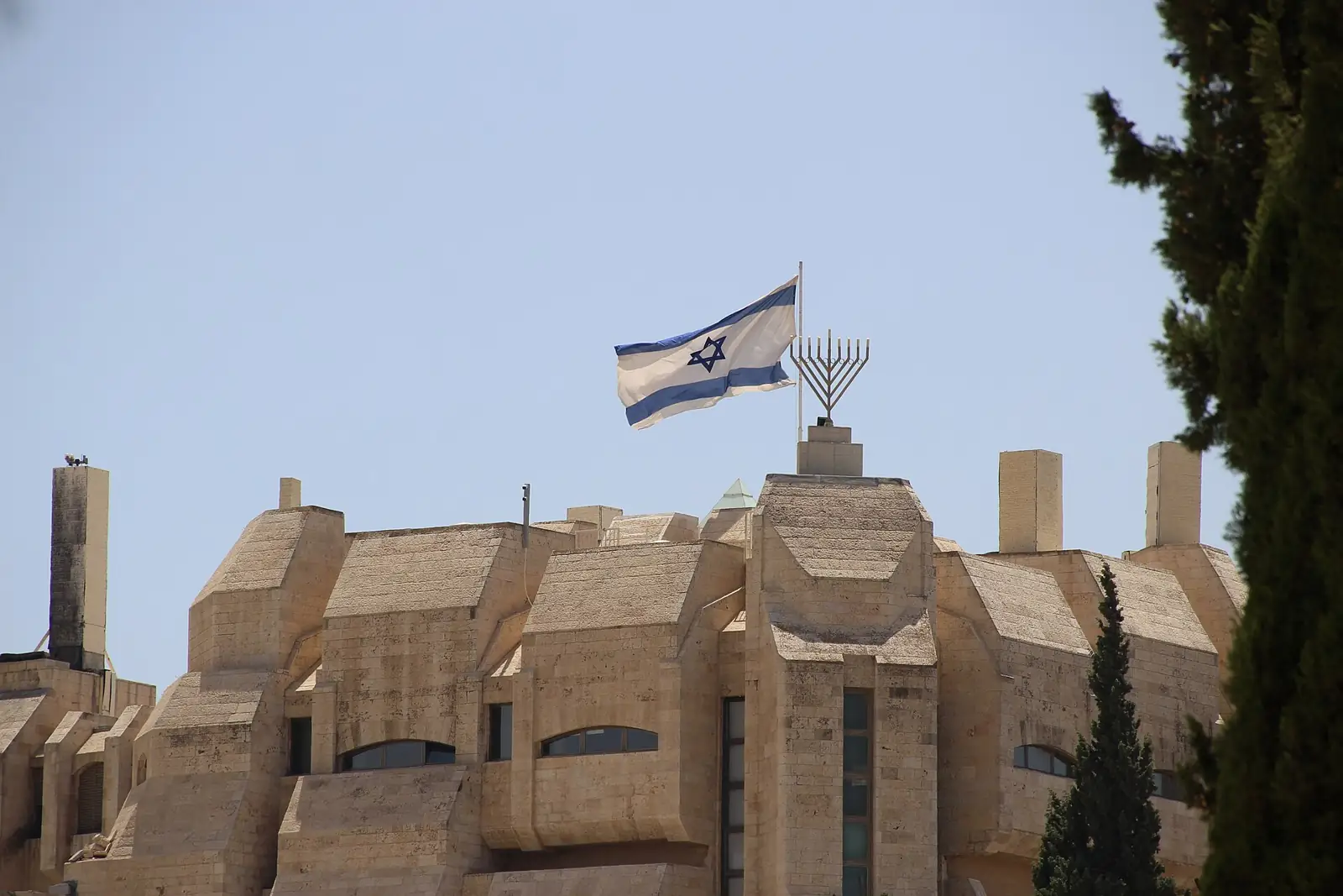 The Israeli flag and a menorah atop a stone building in Jerusalem